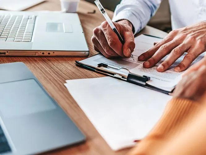 Man filling out a medical claims processing form, representing the meticulous steps involved in medical billing services.